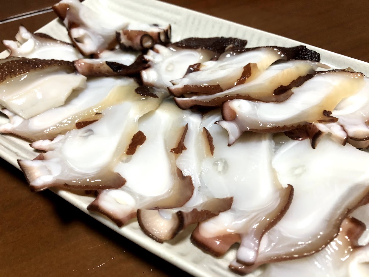 白い皿に盛り付けた薄切りのタコの刺身