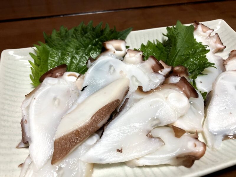 四角い皿に敷いた大葉の上に盛り付けたタコの刺身