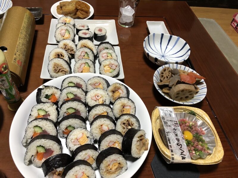手作りの巻き寿司とネギトロ、稲荷寿司、煮物が並ぶ食卓